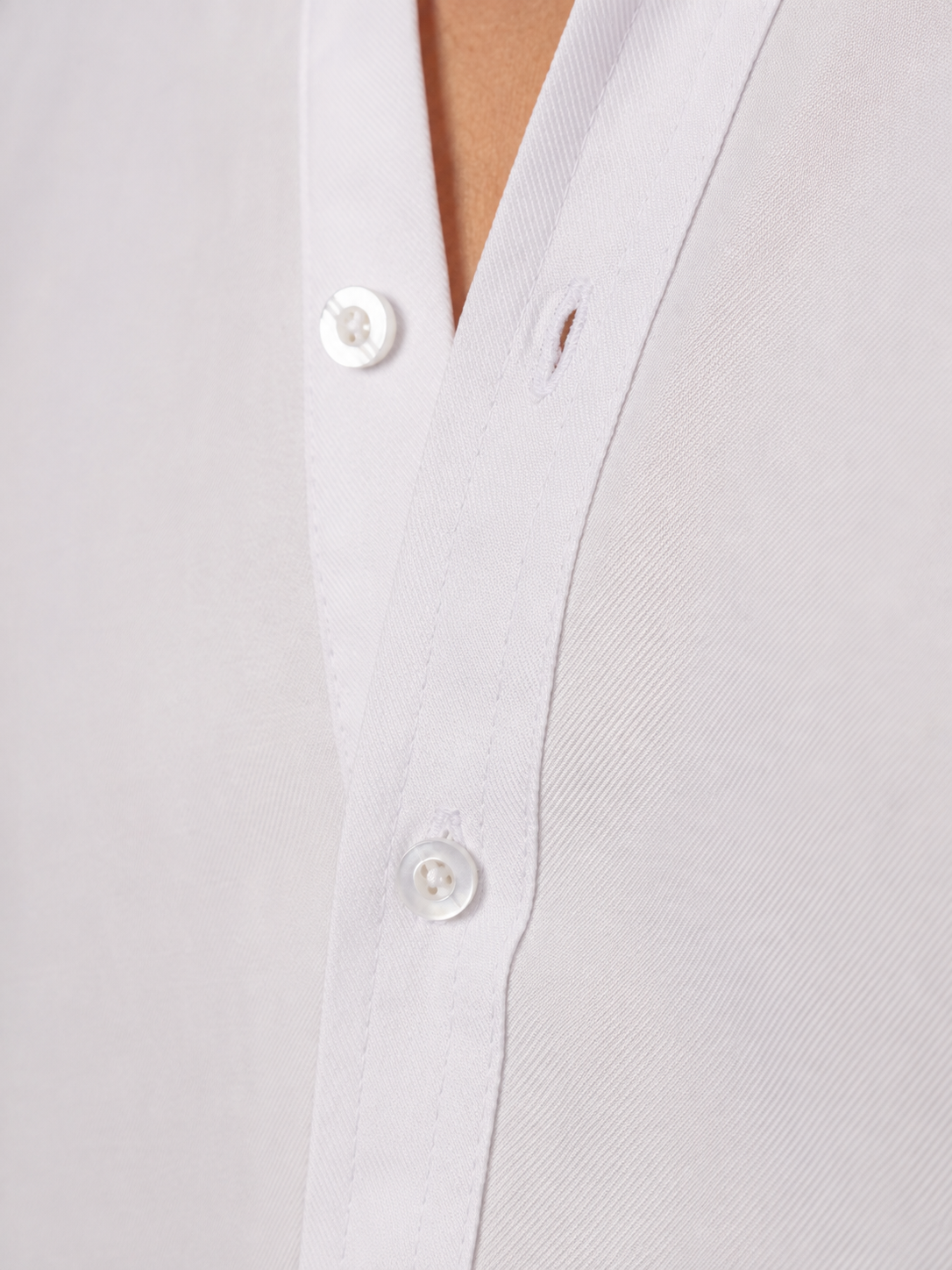 Close-up of a white button-down shirt with white buttons, showing the collar and front placket on a model.