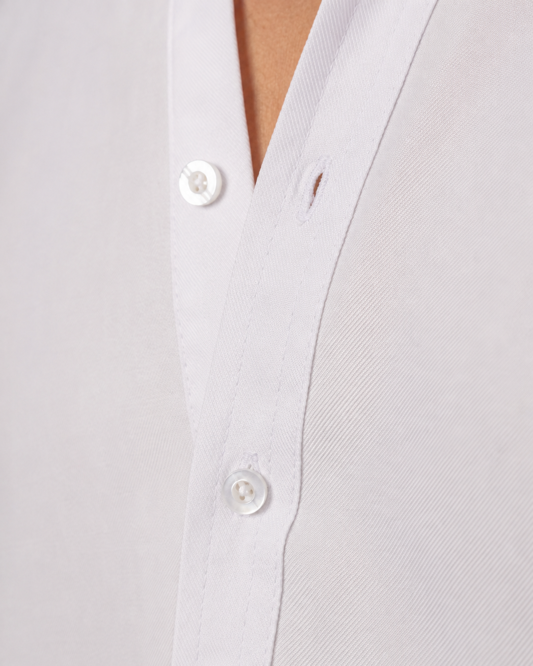 Close-up of a white button-down shirt with white buttons, showing the collar and front placket on a model.